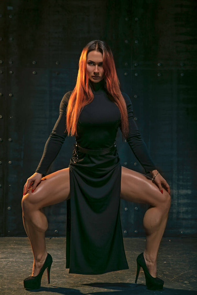 Attractive red-haired girl in black dress demonstrates athletic legs - Foto, Imagen