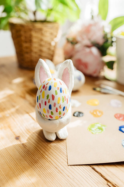 Hand painted easter egg inside a handmade easter bunny egg cup - Фото, изображение