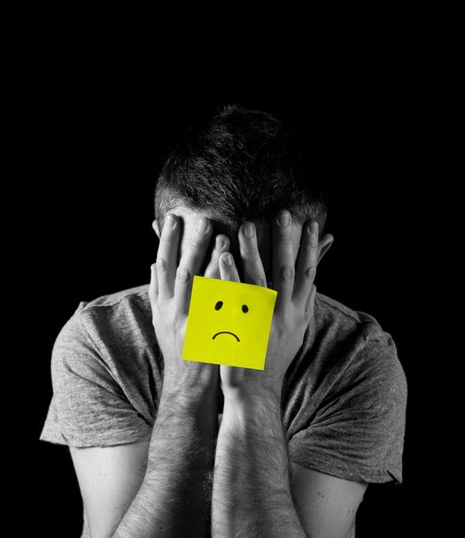 Jonge man die lijden aan depressie en stress alleen met droevig gezicht post-it note - Foto, afbeelding
