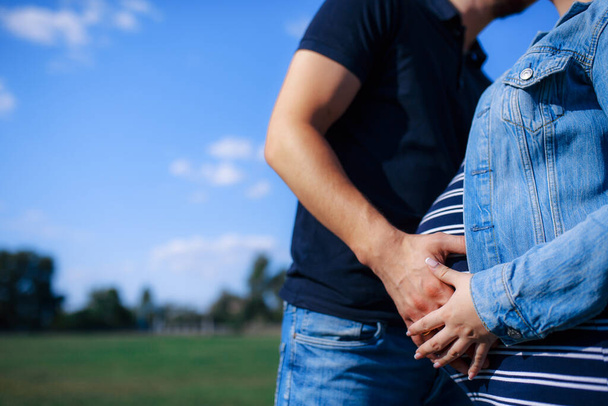 Kocasının kollarında hamile bir kadın. Yaz güneşli hava. Birbirine aşık bir çift sarılıyor.. - Fotoğraf, Görsel