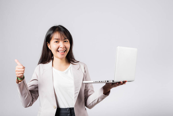 Woman smile confident smiling face hold using laptop computer and showing thumb up for like gesture, Portrait excited Asian young female person businesswoman studio shot isolated on white background - Photo, Image