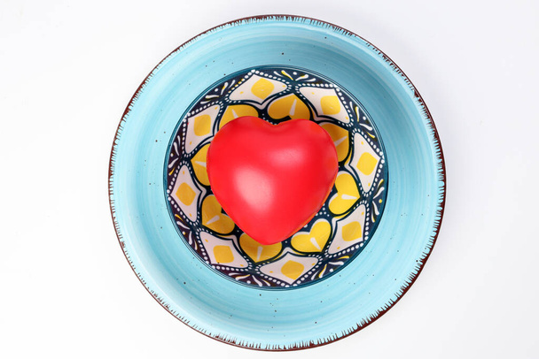 κεραμικό διακοσμημένο μπολ τροφίμων μπλε πιάτο με τρεις διαστάσεις 3d κόκκινο hart σύμβολο μέσα σε λευκό φόντο αντίγραφο κείμενο χώρο πάνω άποψη - Φωτογραφία, εικόνα