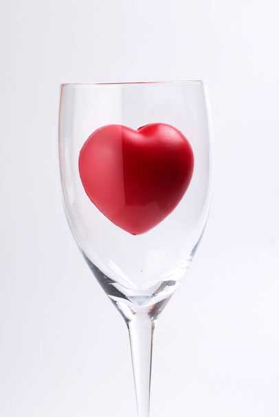 διαφανές γυαλί κρασιού με τρεις διαστάσεις 3d κόκκινο hart σύμβολο μέσα σε λευκό φόντο αντίγραφο χώρο κειμένου - Φωτογραφία, εικόνα