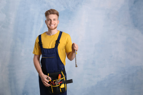 Handsome young plumber on color background - Foto, imagen