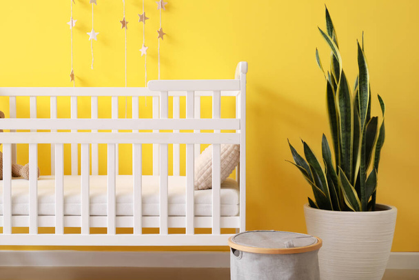 Modern children's room with comfortable crib near color wall - Фото, зображення