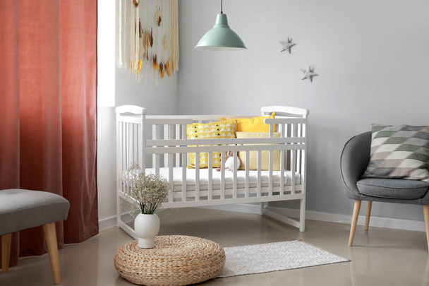 Interior of stylish children's room with comfortable armchair and beautiful crib - Foto, imagen