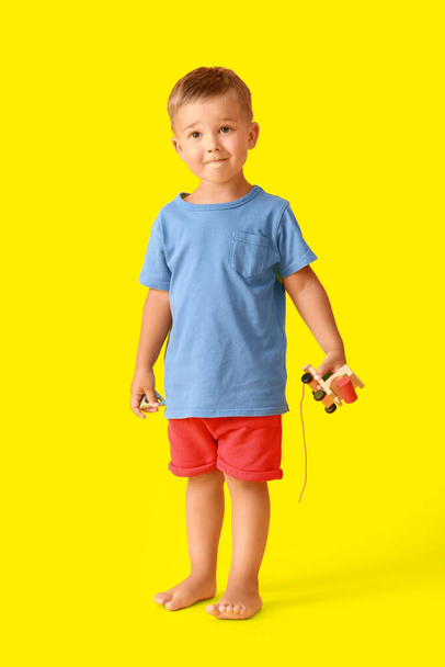 Sarı arka planda tahta oyuncakları olan sevimli küçük bir çocuk. - Fotoğraf, Görsel