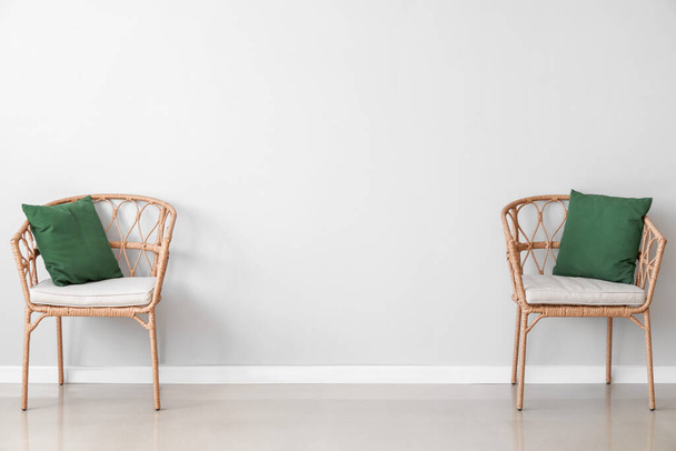 Wicker chairs near light wall in room - Zdjęcie, obraz