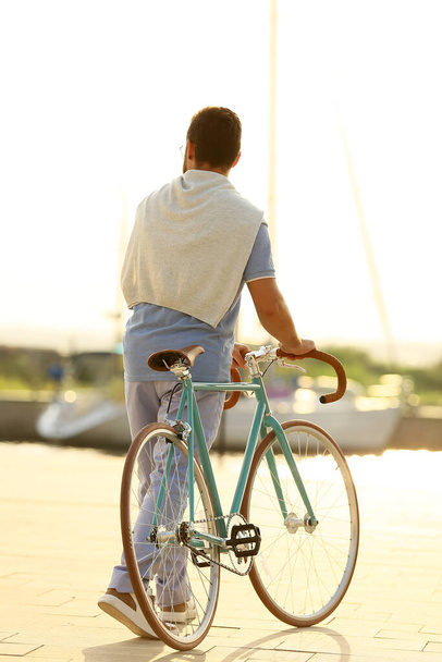 Handsome man with bicycle on embankment - Photo, Image
