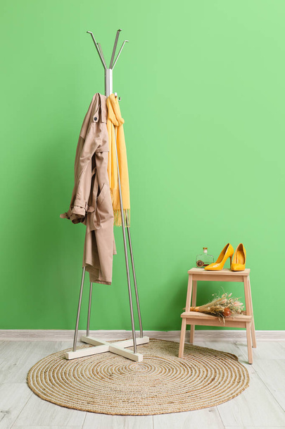 Appendiabiti con giacca e sciarpa vicino parete verde - Foto, immagini