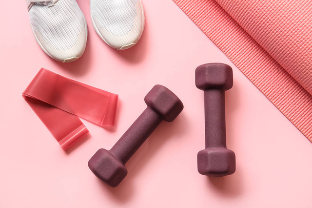 Stylish dumbbells, elastic band and shoes on pink background - Фото, изображение