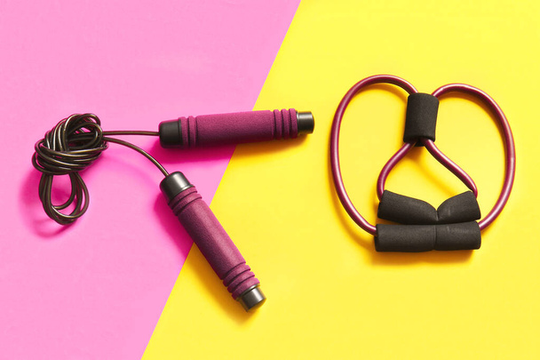 Stylish skipping rope and fitness expander on color background - Photo, Image