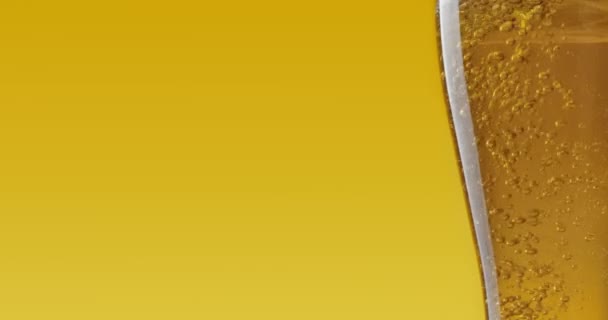 Verter cerveza fresca en vaso sobre fondo amarillo, primer plano - Imágenes, Vídeo