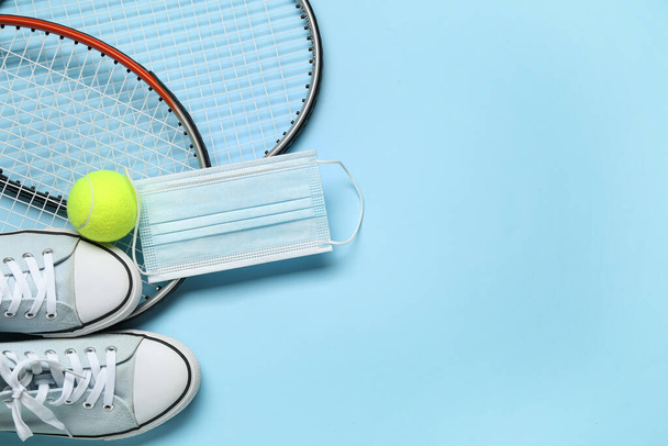 Tennis apparatuur, schoenen en medisch masker op kleur achtergrond - Foto, afbeelding