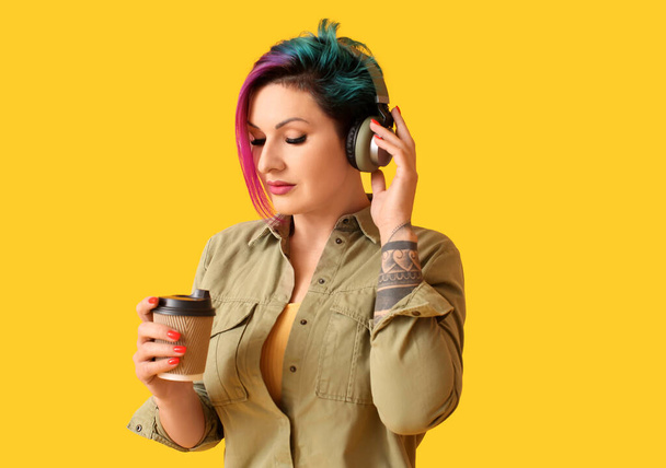 Beautiful woman with unusual hair listening to music on yellow background - Photo, Image