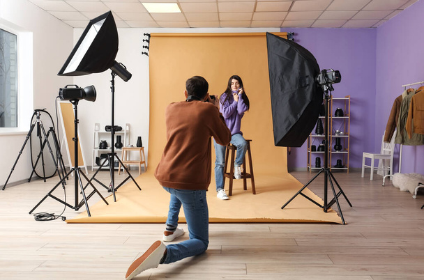 mężczyzna fotograf biorąc zdjęcia młody kobieta siedzi na stołku w studio - Zdjęcie, obraz