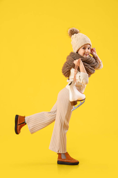 Πηγαίνοντας κοριτσάκι με χειμωνιάτικα ρούχα και με παγοπέδιλα στο φόντο χρώμα - Φωτογραφία, εικόνα