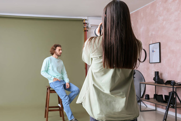 Female photographer taking picture of young man in studio - 写真・画像
