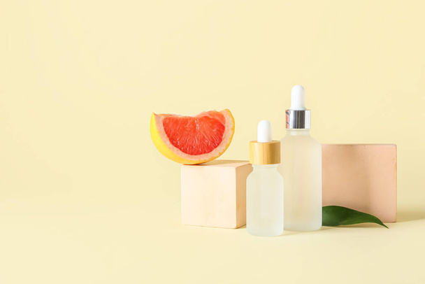 Composición con botellas de aceite esencial, rodajas de pomelo y decoración sobre fondo de color - Foto, imagen