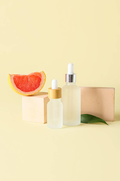 Composition with bottles of essential oil, grapefruit slice and decor on color background - Fotó, kép