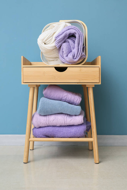 Různé pletené svetry na stole v blízkosti barevné stěny v pokoji - Fotografie, Obrázek