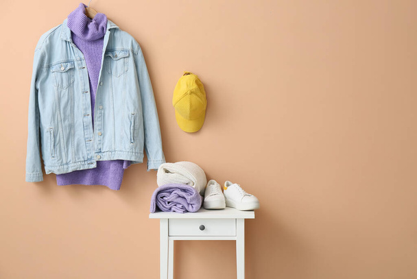 Stílusos ruhák és cipők az asztalon a színes fal közelében - Fotó, kép