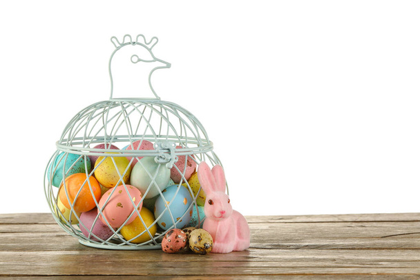 Koš namalovaných velikonoční vajíčka a králíček na stole proti bílému pozadí - Fotografie, Obrázek