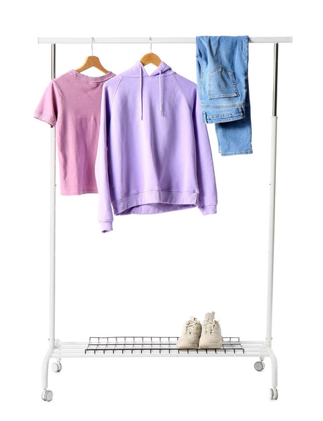 Rack met vrouwelijke kleding en sneakers op witte achtergrond - Foto, afbeelding