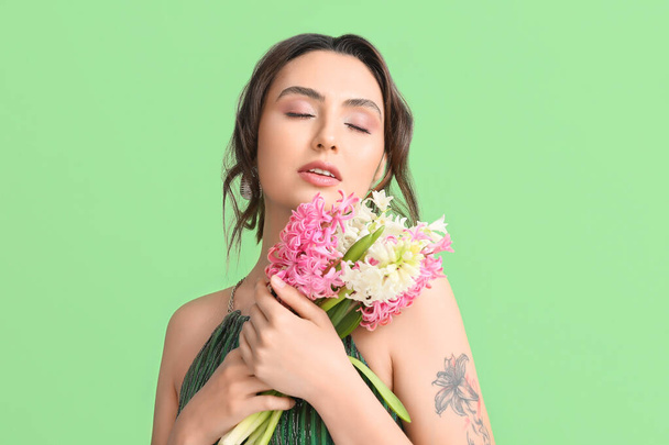 Kaunis nuori nainen hyasintti kukkia vihreällä taustalla - Valokuva, kuva