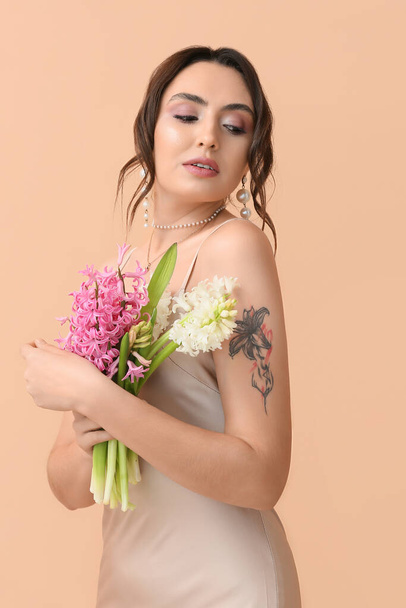 Jolie jeune femme avec des fleurs de jacinthe sur fond de couleur - Photo, image