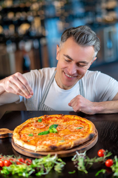 A chef making topping on a italian pizza - Valokuva, kuva