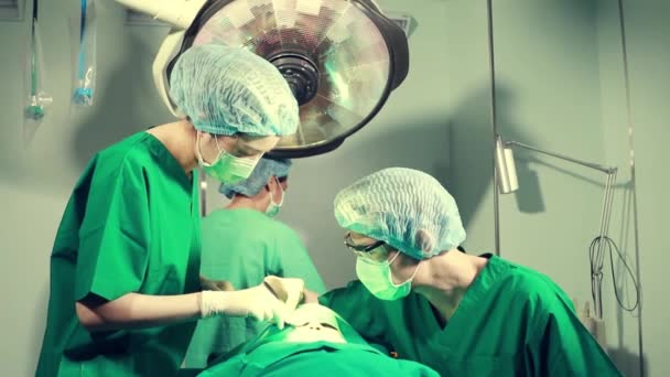 Cerrah ve estetik uzmanlarından oluşan bir ekip modern bir ameliyathanede yüksek kaliteli silikon burun büyütme ameliyatı için bir kadın hastaya ameliyat yapıyorlar.. - Video, Çekim