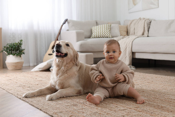 Cute little baby with adorable dog on floor at home - Foto, afbeelding