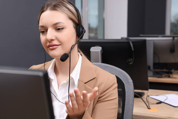 Young call center operator with headset working in modern office - Fotó, kép