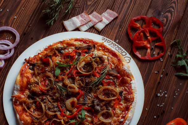 pizza con carne y verduras en una mesa de madera  - Foto, Imagen
