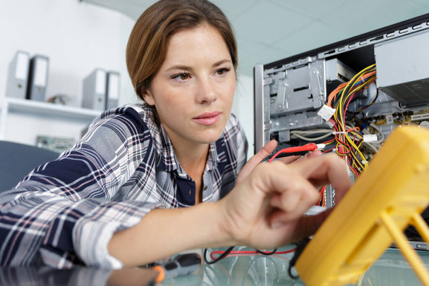portrait of a woman fixing a computer at work - Fotoğraf, Görsel