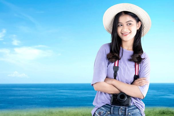 Asian woman with hat and camera standing with blue sky background - Foto, Bild