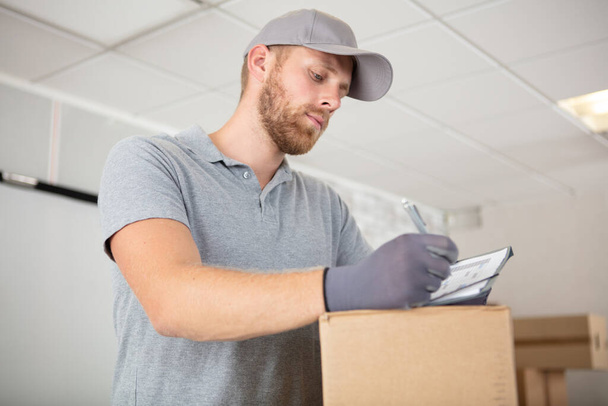 young delivery man holding a cardboard box - Фото, зображення