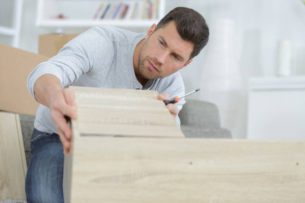 a man assembling wooden furniture - Фото, изображение