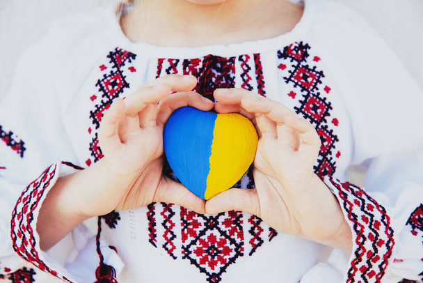 Ragazza in ricamo o camicia ricamata tenere forma di cuore con bandiera Ukrane - Foto, immagini