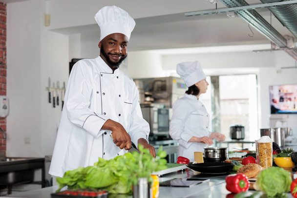 Selbstbewusster Chefkoch in der professionellen Restaurantküche, schneidet Gemüse und bereitet Garnitur für das Abendessen Gericht Rezept. - Foto, Bild