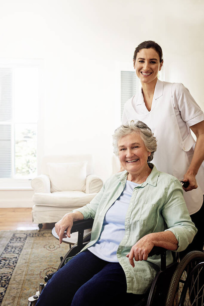 Youre in good hands with her. Portrait of a smiling caregiver and a senior woman in a wheelchair at home. - Foto, imagen