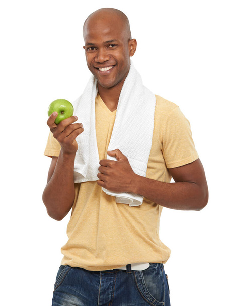 彼は健康的な選択をしている。魅力的な民族の男のショット彼の首の周りにタオルでリンゴを保持. - 写真・画像