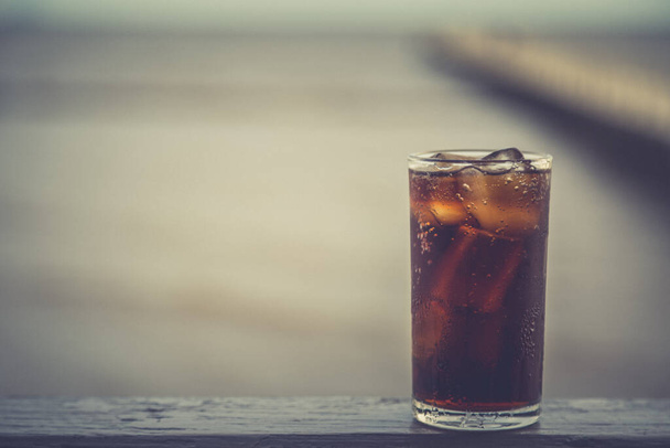 Cola con ghiaccio nel bicchiere pronta da bere per rinfrescarsi su fondo sfocato - Foto, immagini