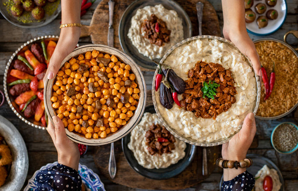 Sokféle étel a családtagok kezében. Helyi ételek, Hunkar Begendi és Eli Nohut. Iftar koncepció. A helyi házi készítésű élelmiszerek változatossága.    - Fotó, kép