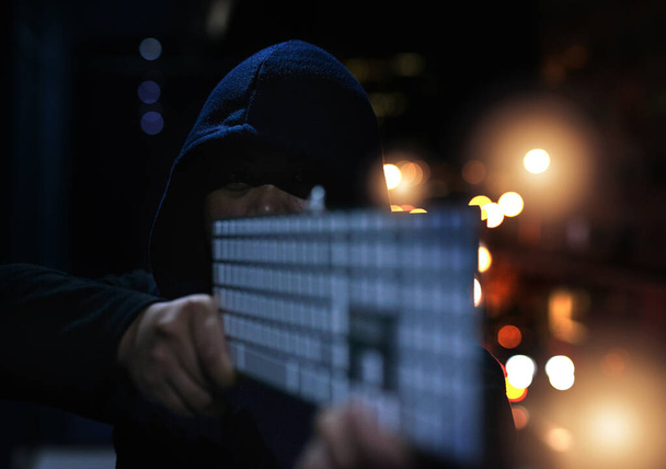 Silahlandı ve verilerinizi yok etmeye hazır. Karanlıkta elinde klavye tutan tanınmayan bir hackerın fotoğrafı.. - Fotoğraf, Görsel