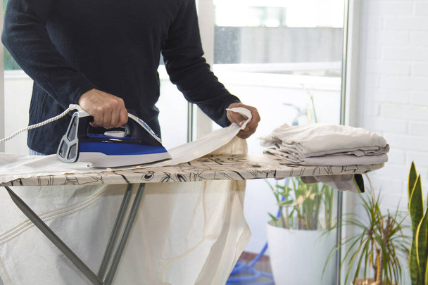 man ironing at home with iron, concept of equality in housework - Foto, Bild