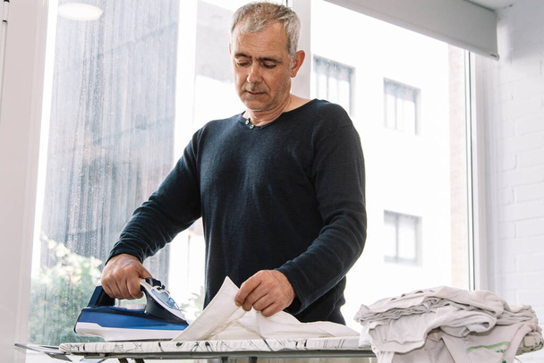 man with iron ironing shirt - Fotografie, Obrázek