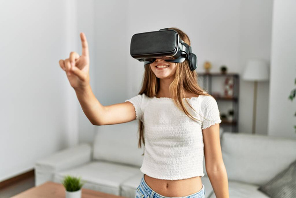 Evde video oyunu oynayan sevimli bir kız VR gözlük kullanıyor. - Fotoğraf, Görsel