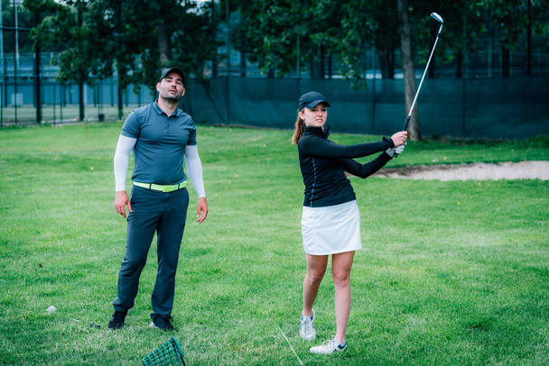 ゴルフを学ぶ。ゴルフ場で若い女性とゴルフインストラクター - 写真・画像